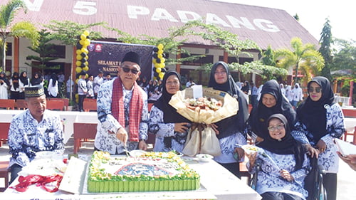 Azwarman kepala sekolah SMAN 5 Padang di dampingi pengawas dari Dinas Pendidikan Provinsi Sumbar dan lainnya sedang memotong kue Hut hari guru tahun 2023