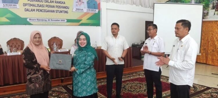 Upaya Tuntaskan Masalah Stunting, Dinas PMN Laksanakan Bimtek Optimalkan Peran Posyandu 1 SERAHKAN—Ketua TP-PKK Kabupaten Sijunjung, Ny. Riri Benny Dwifa, serahkan bahan Bimtek usai pembukaan.