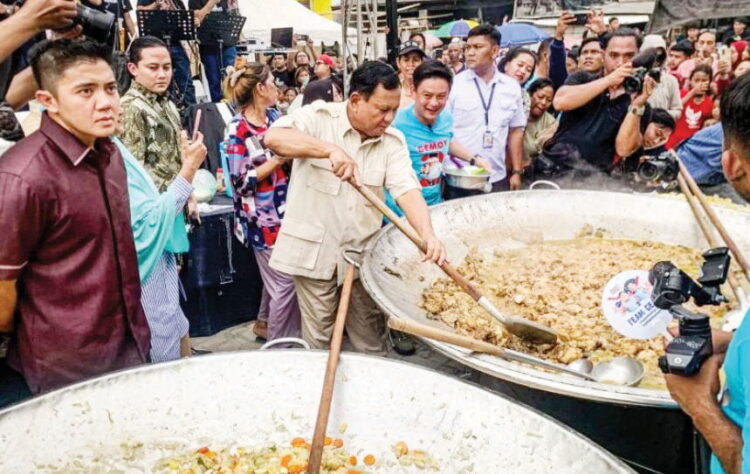 ADUK MASAKAN— Capres nomor urut 2 Prabowo Subianto (tengah) didampingi konten kreator Bobon Santoso mengaduk masakan saat acara Makan Besar bersama di Cilincing, Jakarta Utara.