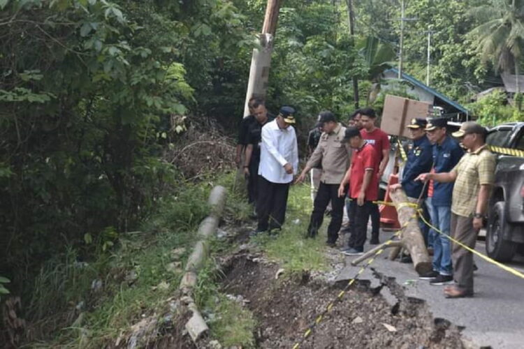 JALAN AMBLAS—  Penjabat Wali Kota Sawahlunto Dr. Zefnihan, mendampingi Gubernur Sumatera Barat Mahyeldi Ansharullah saat meninjau tbadan jalan yang amblas ke sungai.