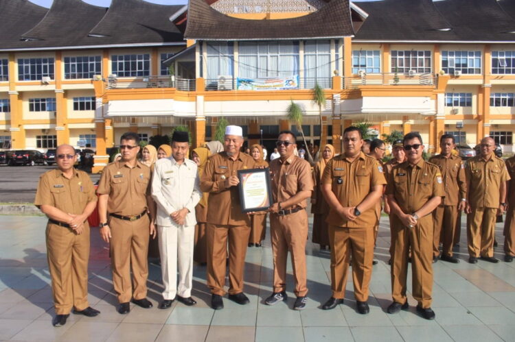 LIHATKAN PENGHARGAAN— Bupati Pasbar Hamsuardi didampingi Wakil Bupati Risnawanto, Sekda Hendra Putra, Staf Ahli, Asisten dan OPD dengan sejumlah penghargaan yang diraih selama 2023, saat  apel gabungan perdana tahun 2024 di halaman Kantor bupati.