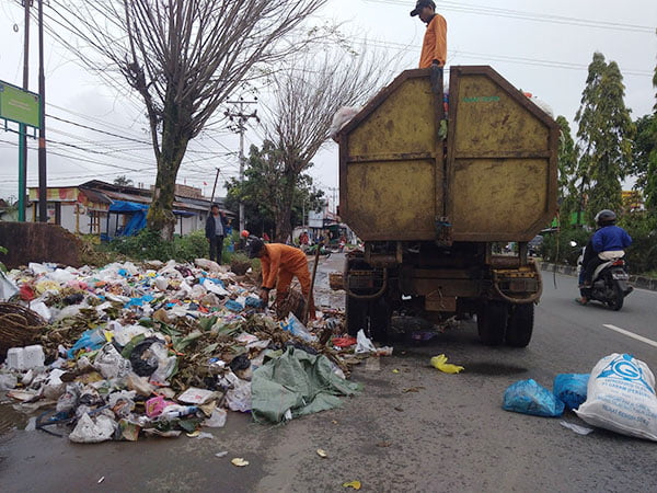 DARURAT SAMPAH— Petugas kebersihan mengambil tumpukan sampah yang sudha berserakan di jalan Sukarno Hatta, Kota Payakumbuh.