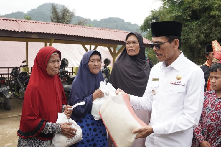 DISTRIBUSIKAN BANTUAN BERAS— Bupati Limapuluh Kota Safaruddin saat mendistribusikan bantuan cadangan beras dari pemerintah kepada keluarga tidak mampu.