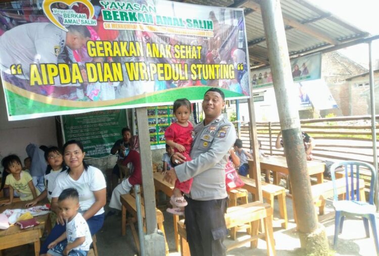 GENDONG ANAK— Aipda Dia Wihendro Ratno sedang menggendong anak usai berikan asuipan gizi.