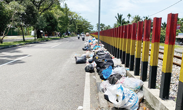 TUMPUKAN SAMPAH— Pemandangan berupa tumpukan sampah dijumpai di pinggir-pinggir jalan raya Adinegoro-Lubuk Buaya, Kecamatan Kototangah, Rabu (21/2) siang. Sampah rumah tangga yang dibungkus plasti itu diletakkan begitu saja oleh warga dan tidak diangkut petugas kebersihan kota.