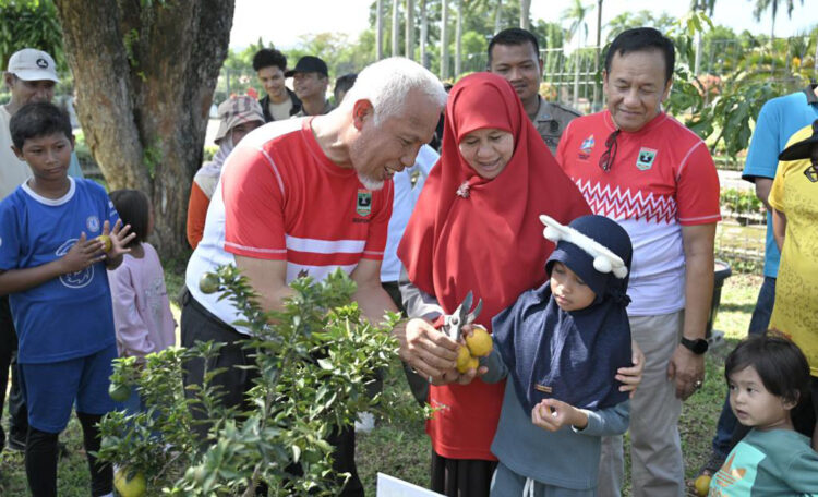 PETIK BUAH—Gubernur Sumbar Mahyeldi Ansharullah bersama Ketua TP PKK Sumbar, Ny Hj Harneli Mahyeldi mengedukasi anak mengenal lingkungan dengan mengajarkan memetik buah.