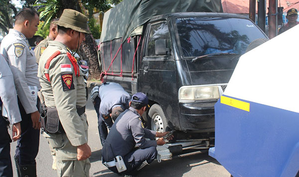 DIDEREK PETUGAS— Petugas gabungan Satpol-PP dan Dinas Perhubungan (Dishub), Jumat (15/3) pagi, menderek mobil toko yang berjualan di badan jalan, kawasan Jati, Kecamatan Padang Timur.