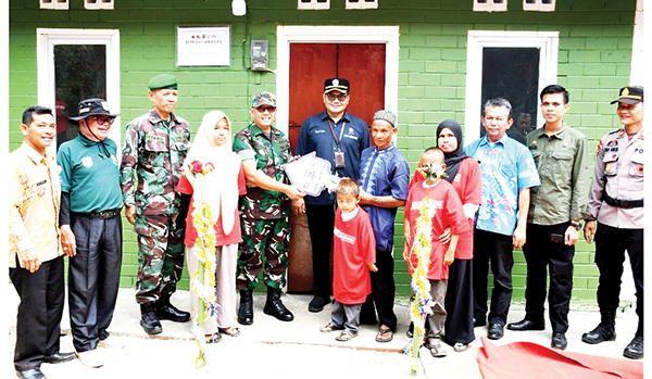 Tangisan Bahagia Netri Menerima Rumah Bantuan TMMD dari Semen Padang 1 PENYERAHAN KUNCI— Kasiter Korem 032/Wirabraja Kolonel Inf. Indra Padang, menyerahkan replika kunci rumah kepada Jon Firman (51), yang merupakan suami dari Netri Mulyati, pemilik rumah yang dibangun TNI AD melalui program TMMD dari PT Semen Padang, Kamis (25/4).