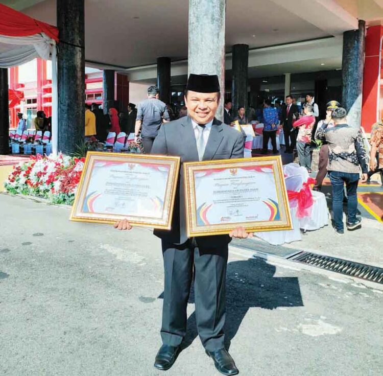 Peringatan Hari Pendidikan Nasional dan Hari OTDA, Kabupaten Agam Raih Dua Penghargaan Bergengsi 1 PENGHARGAAN— Staf Ahli Bupati Bidang Hukum, Politik, dan Pemerintahan, Fauzi, memperlihatkan dua penghargaan yang diraih Kabupaten Agam pada Hari Pendidikan Nasional dan Hari Otonomi Daerah (OTDA) yang diselenggarakan di Kantor Gubernur Sumbar, Kamis (2/5).