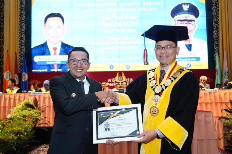 ORASI ILMIAH— Bupati Tanahdatar Eka Putra saat menerima piagam dari Rektor UNP Krismadinata, Ph.D, usai memberikan orasi ilmiah saat acara wisuda UNP .