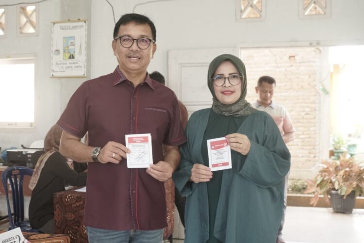 GUNAKAN HAK PILIH— Bupati Solok Selatan H Khairunas beserta Ketua TP PKK, Ny. Erniati Khairunas lihatkan tanda memilih.