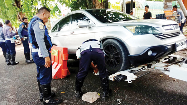KEMPESI DAN DEREK MOBIL— Petugas gabungan Dishub bersama TNI/Polri dan Diskominfo melakukan pengempesan dan menderek sejumlah mobil yang masioh parkir sembarangan di kawasan Khatib Sulaiman, Perintis Kemerdekaan dan Sawahan, Selasa (20/8).