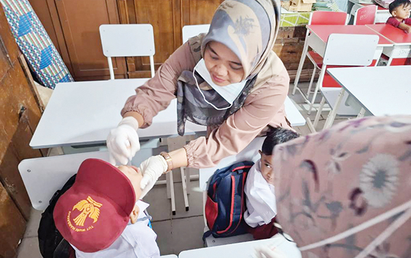 Sasar 96.457 Anak Usia 0-7 Tahun, Pemko Padang Bidik Target 100 Persen PIN Polio 1 TETES POLIO— Petugas Dinkes dan juga Puskesmas menyasar seluruh TK, PAUD, SD di Kota Padang untuk menyukseskan pelaksanaan PIN Polio 2024. Terlihat seorang petugas meneteskan vaksin polio pada pelajar kelas 1 SD.