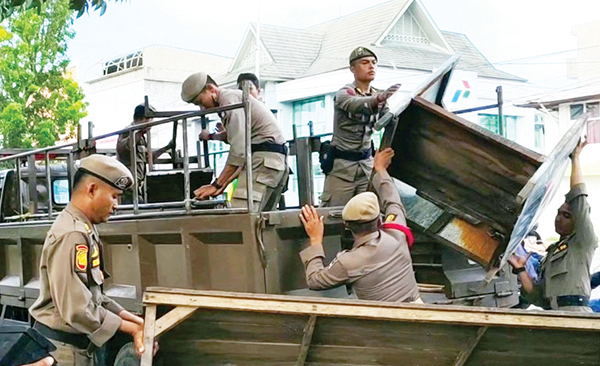 BERSIHKAN LAPAK—Petugas Satpol PP Kota Padang membersihkan dan mengangkut semua lapak-lapak milik PKL yang ditinggal begitu saja oleh pedagang di atas trotoar, di di depan SPBU kawasan Veteran, Kecamatan Padang Barat, Selasa (3/9).