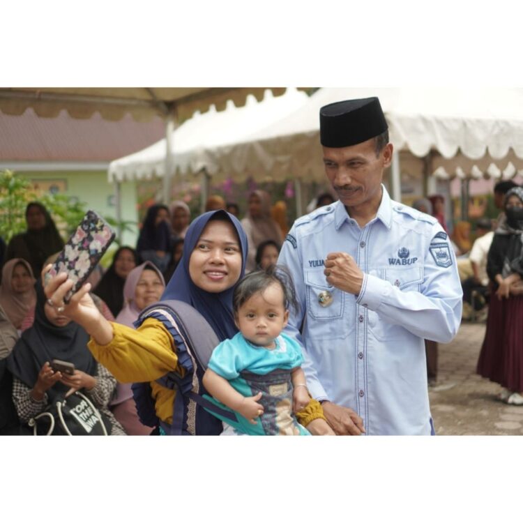Ratusan UMKM Solsel Terima Bantuan Pemerintah 1 BERSUA FOTO—Wakil Bupati Solok Selatan Yulian Efi bersuafoto dengan seorang IRT bersama balita usai serahklan bantuan.