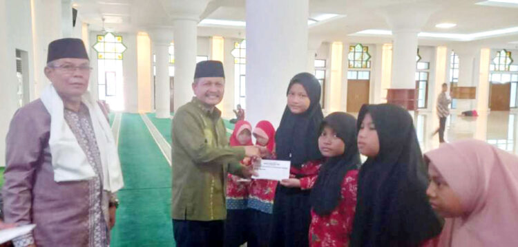 SANTUNAN ANAK YATIM— Kabag Kesra Kota Padang Jasman bersama Ketua Harian Masjid Agung Nurul Iman Prof. Salmadanis, menyerahkan santunan untuk untuk 44 orang anak-anak yatim binaan masjid tersebut, Sabtu (19/10).