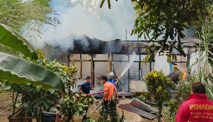 KEBAKARAN— Petugas Damkar melakukan penyemprotan air untuk memadamkan api yang membakar rumah 
dinas guru di SDN 18 Nagari Pematang Panjang, Sijunjung.