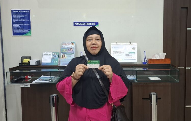 Satu Dekade Program JKN, Helen Buktikan Manfaatnya 1 MANFAAT JKN—Helen Midova saat memperlihatkan kartu program JKN.