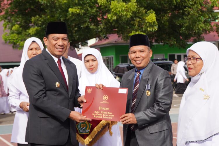 SERAHKAN SATYALENCANA— Penjabat Wali Kota Sonny Budaya Putra, menyerahkan satyalencana kepada ASN Kemenag usai upacara peringatan HAB Kementerian Agama ke-79, di Madrasah Aliyah Negeri (MAN) 1 Padang Panjang, Jumat (3/1).
