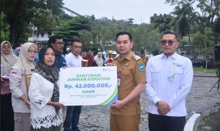 SANTUNAN JKM— Pj Wali Kota Sawahlunto Fauzan Hasan secara simbolis menyerahkan santunan JKM, didampingi Kepala BPJS Ketenagakerjaan Cabang Solok Maulana Anshari Siregar kepada ahli waris Ilham.