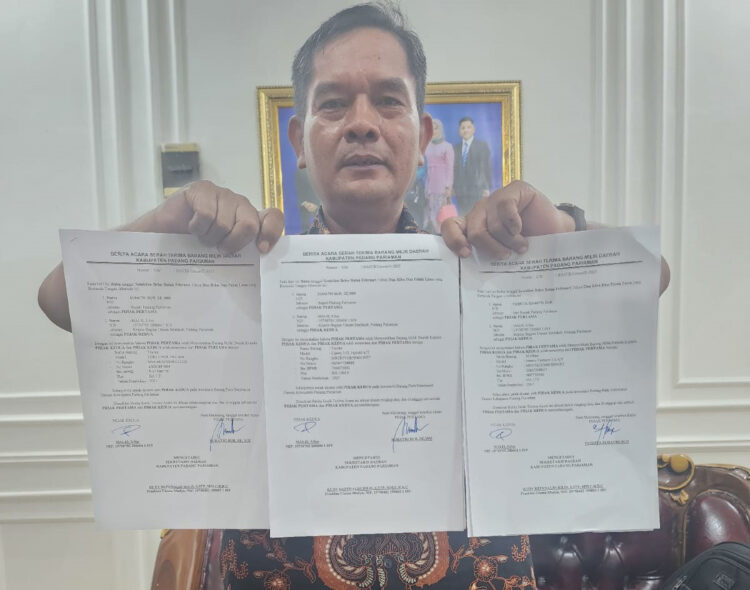 LIHATKAN—Kabag umum Marlis saat perlihatkan berita acara serah terima mobil dinas dan rumah dinas.