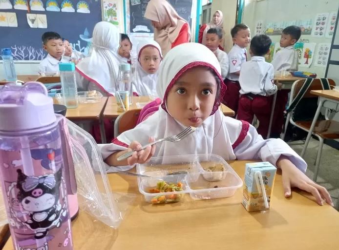 MAKAN BERGIZI GRATIS— Siswi Sekolah Dasar tengah menyantam makanan program Makan Bergizi Gratis.