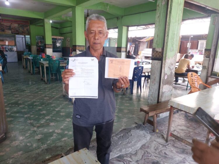 Amril, Pedagang di bangunan lama Fase VII Pasar Raya memperlihatkan bukti keterangan Bank Nagari atas kepemilikan kartu kuning yang menjadi haknya menempati bangunan baru Fase VII Pasar Raya Padang.