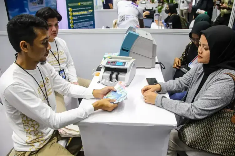 Perbankan Tak Bisa Langsung Turunkan Suku Bunga Kredit usai BI Rate Turun 1 TUKAR UANG—Warga menunjukan uang rupiah usai melakukan penukaran uang baru.
