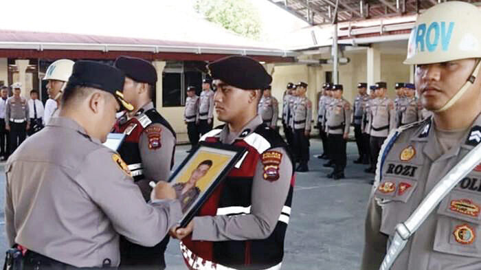 DIPECAT— Kapolres Pariaman AKBP Andrenaldo 
Ademi menyilang foto dua anggota Polisi yang dipecat 
saat upacara PTDH.