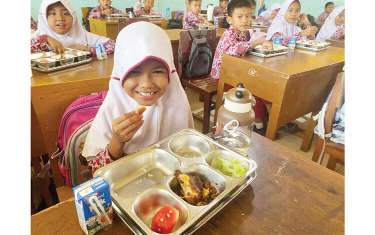 NIKMATI MENU MBG— Sejumlah murid di SDN 09 Aia Pacah, Kecamatan Koto Tangah, menikmati menu MBG perdana di sekolah mereka, Rabu (10/9). Program MBG di sekolah ini dibantu oleh SPPG Hippocrates Yayasan Ghanniyah Maju Berkah.
