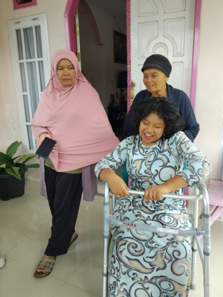 TERSENYUM BAHAGIA— Andini, warga Kelurahan Kampung Manggis, Kecamatan Padang Panjang Barat, tersenyum saat menerima bantuan alat bantu berjalan dari DSPPKBPPPA.