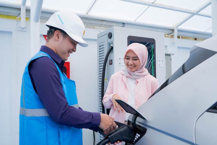 Ilustrasi pengguna electric vehicle dibantu oleh Petugas PLN ketika mengisi kendaraan listriknya di salah satu SPKLU.