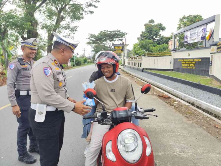 DAPAT BUNGA —Satlantas Polres 50 Kota memberikan bunga kepada pengendera yang lengkap dengan surat-surat kendaraan.