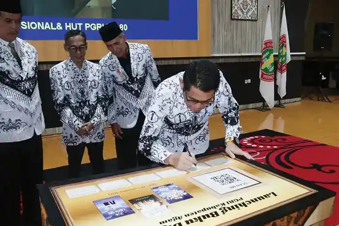 SEMINAR NASIONAL— Plt. Kepala Dinas Pendidikan dan Kebudayaan, Andrinaldi, menandatangani prasasti peluncuran buku digital bersamaan dengan Seminar Nasional dalam rangka memperingati HUT PGRI ke-80 dan Hari Guru Nasional, di UIN Syech Jamil Jambek, Kubang Putih, Selasa (18/11).