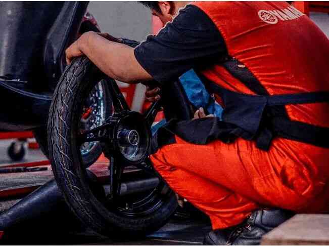 GANTI BAN—Mekanik Yamaha melakukan penggantian ban sepeda motor milik konsumen.
