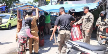 DITERTIBKAN— Petugas Satpol PP Padang menertibkan sejumlah papan merek jualan milik pedagang yang dianggap mengganggu pandangan pengguna jalan, karena diletakkan di bahu jalan, Senin (29/12).