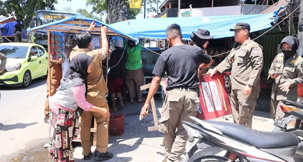 DITERTIBKAN— Petugas Satpol PP Padang menertibkan sejumlah papan merek jualan milik pedagang yang dianggap mengganggu pandangan pengguna jalan, karena diletakkan di bahu jalan, Senin (29/12).