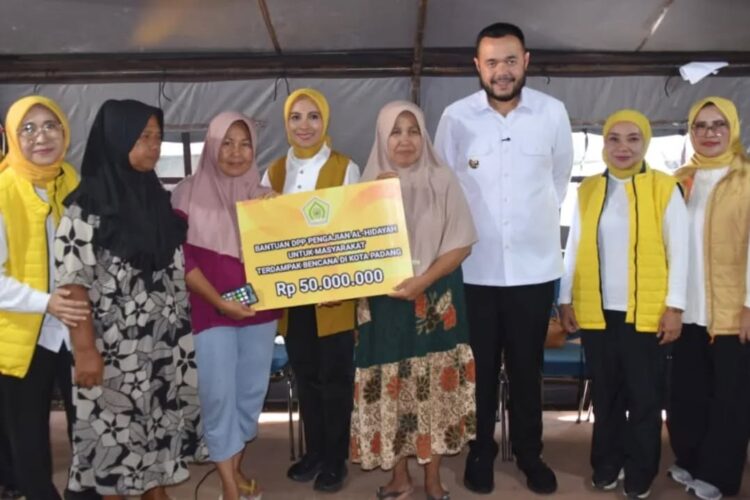 SALURKAN BANTUAN— Penasihat DWP Kementerian ESDM RI, Sri Suparni Bahlil Lahadalia menyerahkan bantuan logistik vital bagi warga terdampak, dan diterima Wako Fadly Amran, di lokasi Huntara Perumahan Nelayan, Kecamatan Koto Tangah, Senin (22/12).