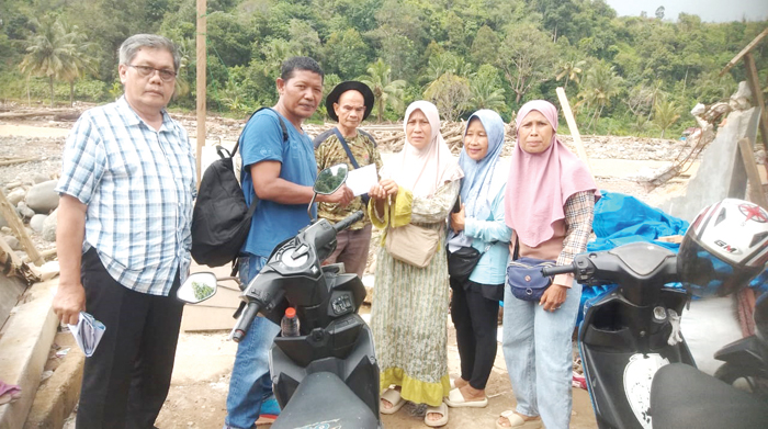 SERAHKAN BANTUAN— Delvi Adri, didampingi Ketua IKBM H Adrianas dan penasehat Afrizal serahkan bantuan pada Susi warga Batu Busuak.