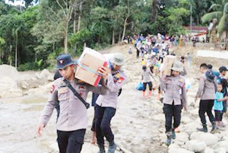 SALURKAN BANTUAN— Puluhan personel Polda Sumbar berjalan kaki mengangkut bantuan logistik untuk warga Kampung Kunyik, Kecamatan Palembayan, yang terisolasi akibat bencana banjir bandang dan longsor.