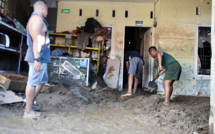 BERSIHKAN LUMPUR— Korban terdampak banjir tengah membersihkan sisa lumpur akibat banjir.
