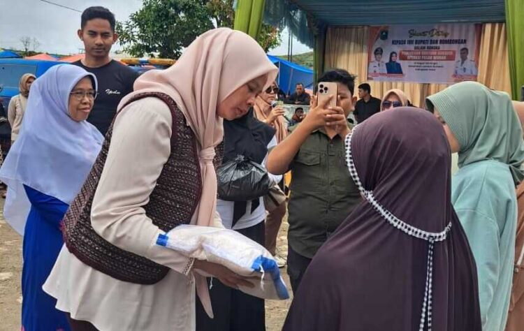 Pemkab Solok Gelar Pasar Murah, Ringankan Ekonomi Masyarakat Terdampak Bencana 1 BANTUAN BERAS— Ketua Dekranasda Kabupaten Solok, Ny. Nia Jon Firman Pandu, menyerahkan bantuan beras pada warga saat kegiatan Pasar Murah, Senin (15/12).