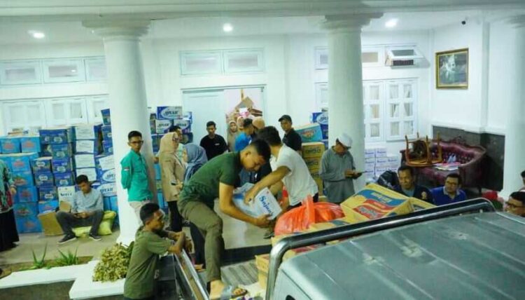 PENYALURAN BANTUAN—Para relawan dan tim penyelamat saat menaikkan bantuan ke atas mobil untuk dikirim kepada korban terdampak bencana banjir dan banjir bandang.