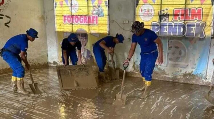 BERSIHKAN KELAS— Aparat kepolisian ikut membersihkan ruangan kelas SMA 1 Batang Anai yang masih digenangi lumpur pascamusbah banjir bandang akhir November lalu.