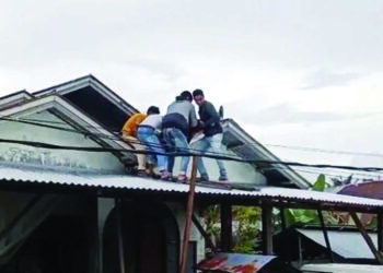 EVAKUASI KORBAN— Warga menurunkan korban yang tersetrum di atap rumahnya, Sabtu (13/12) siang