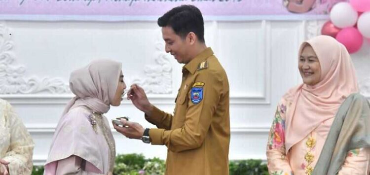 SUAPAN—Wali Kota Sawahlunto Riyanda Putra suapan kue kepada Ketua TP PKK Sawahlunto Yori.
